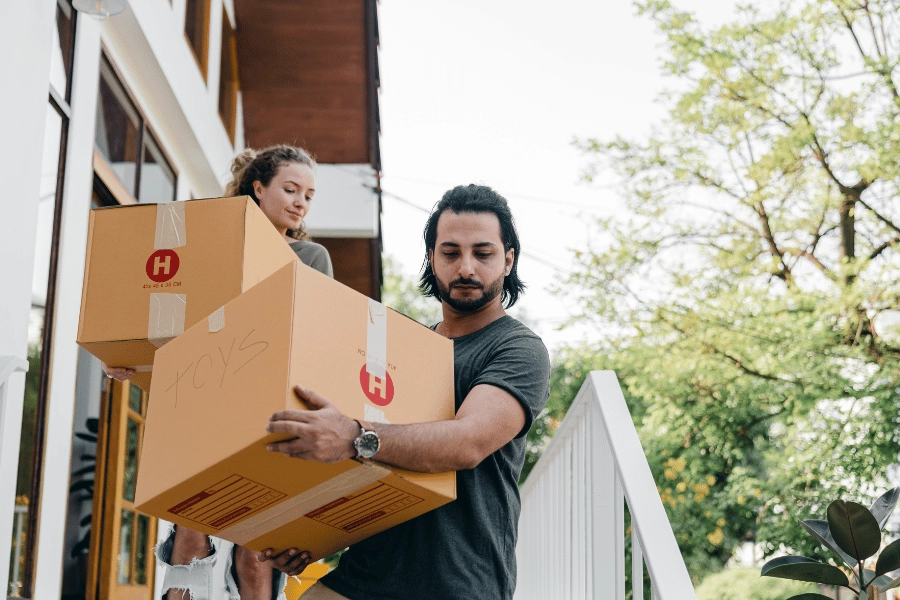 couple carrying boxes downstairs during a move 
